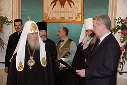Сергей Собянин (справа) зачитал Алексию II (слева) поздравление президента Владимира Путина. Загружается с сайта Ъ